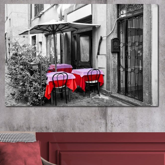 tablou canvas cu o cafenea pe o strada, redata in alb si negru, cu mese decorate cu rosu, intr-un peisaj vintage