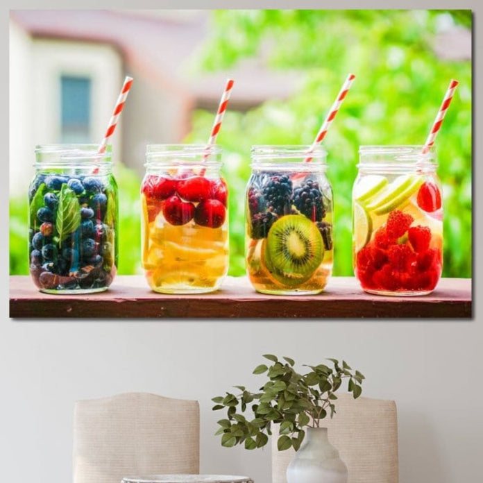 tablou canvas cu patru pahare cu suc si fructe precum afine, cirese, kiwi, zmeura, lamaie, mure si paie colorate, pe fundal cu vegetatie verde