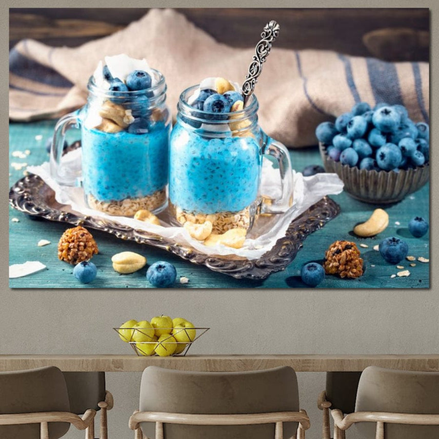 Tablou Canvas Premium LuxCanva® N1089 "Armonie Albastra" prezintă două borcane cu budincă de chia, afine, granola și alune, pe o tavă cu fructe și nuci, ideal pentru restaurant sau bucătărie. Calitate premium by LuxCanva®.