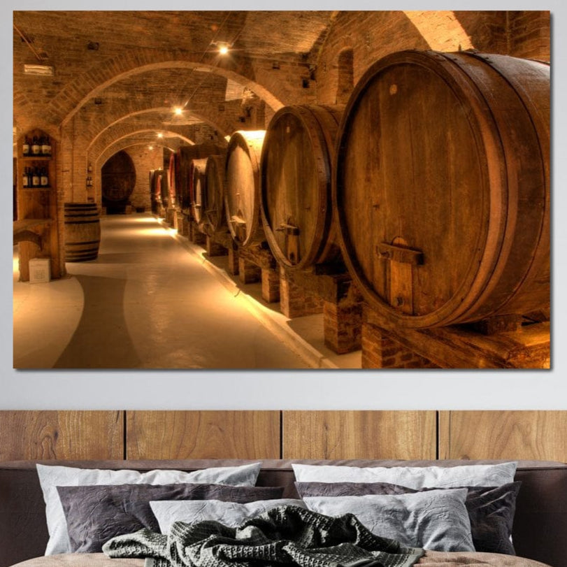 tablou canvas cu butoaie de vin, intr-un subteran in lumina calda, alaturi de sticle de vin si pereti de caramida