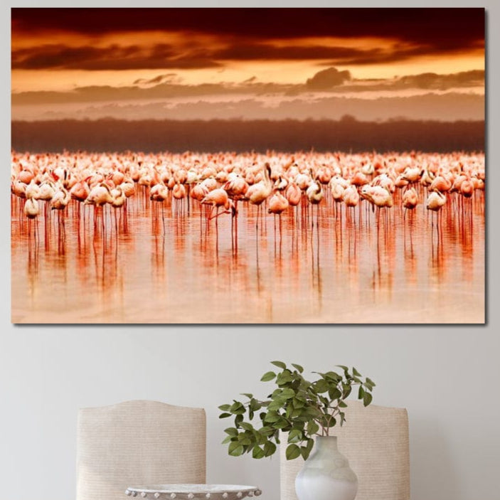 tablou canvas cu un stol de flamingo roz pe apa, sub cer cu apus indian