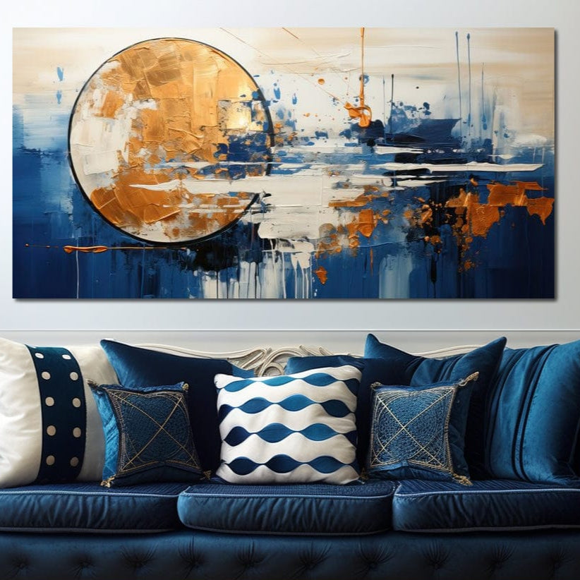 O cameră de zi modernă are o canapea albastră cu perne sub LuxCanva® Tablou Canvas Premium, J1017 - artă de perete abstractă care prezintă tușe de pensulă aurii, albastre și albe, cu un cerc auriu texturat în imprimare calitate premium.