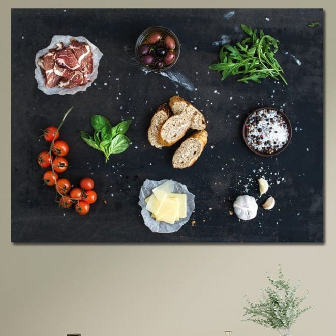tablou canvas cu bruschette, rosii cherry, verdeturi, condimente si prosciutto pe o masa neagra