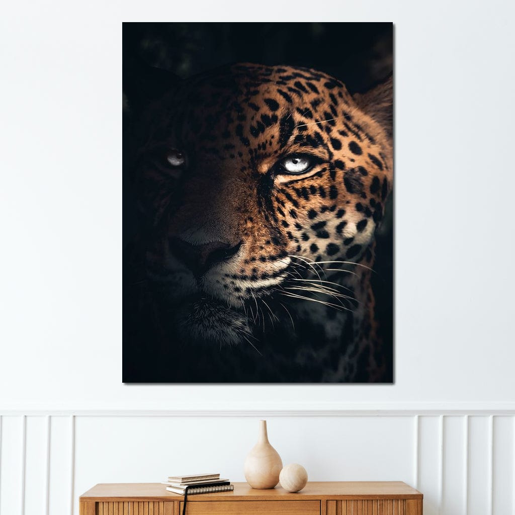tablou canvas cu un chip de jaguar, cu ochi albastri, surprins in umbra pe fundal intunecat