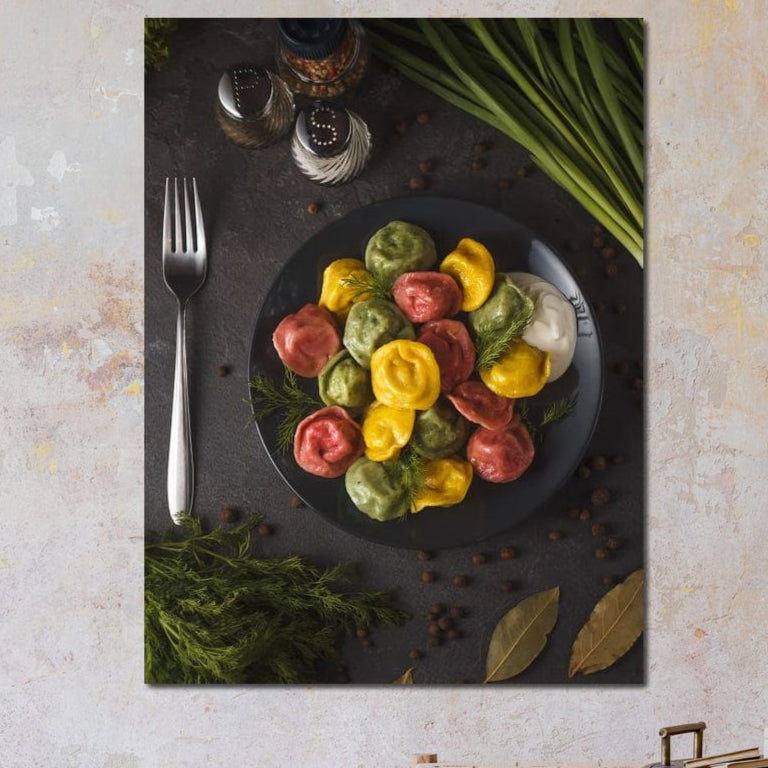 O farfurie vibrantă de ravioli în roșu, galben și verde cu ierburi, condimente și sos alb inspiră Tablou Canvas Premium LuxCanva® N1001 - Deliciu in Nuante: perfect pentru decorul bucătăriei sau al restaurantului. Brand: LuxCanva®.