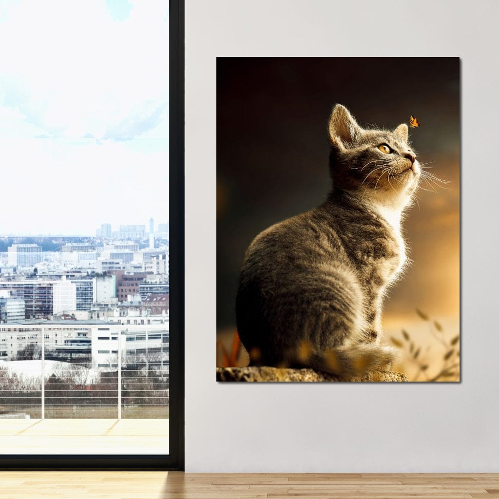 tablou canvas cu o pisica mica privind un fluture, pe fundal natural in lumina calda de apus