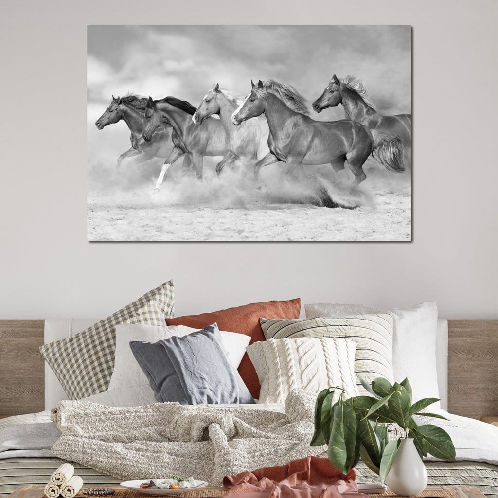 tablou canvas cu un grup de cai in galop prin nisip, redati in nuante de alb si negru, pe fundal cu nori