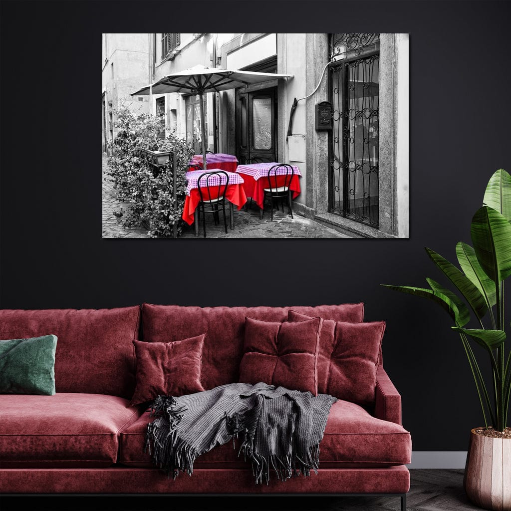 tablou canvas cu o cafenea pe o strada, redata in alb si negru, cu mese decorate cu rosu, intr-un peisaj vintage