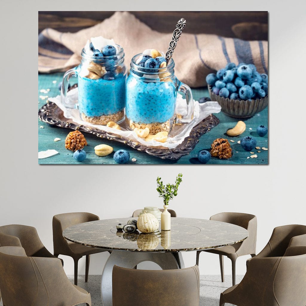 tablou canvas cu doua deserturi cu seminte de chia, afine si alune, pe o tava argintie, pe o masa albastru - turcoaz