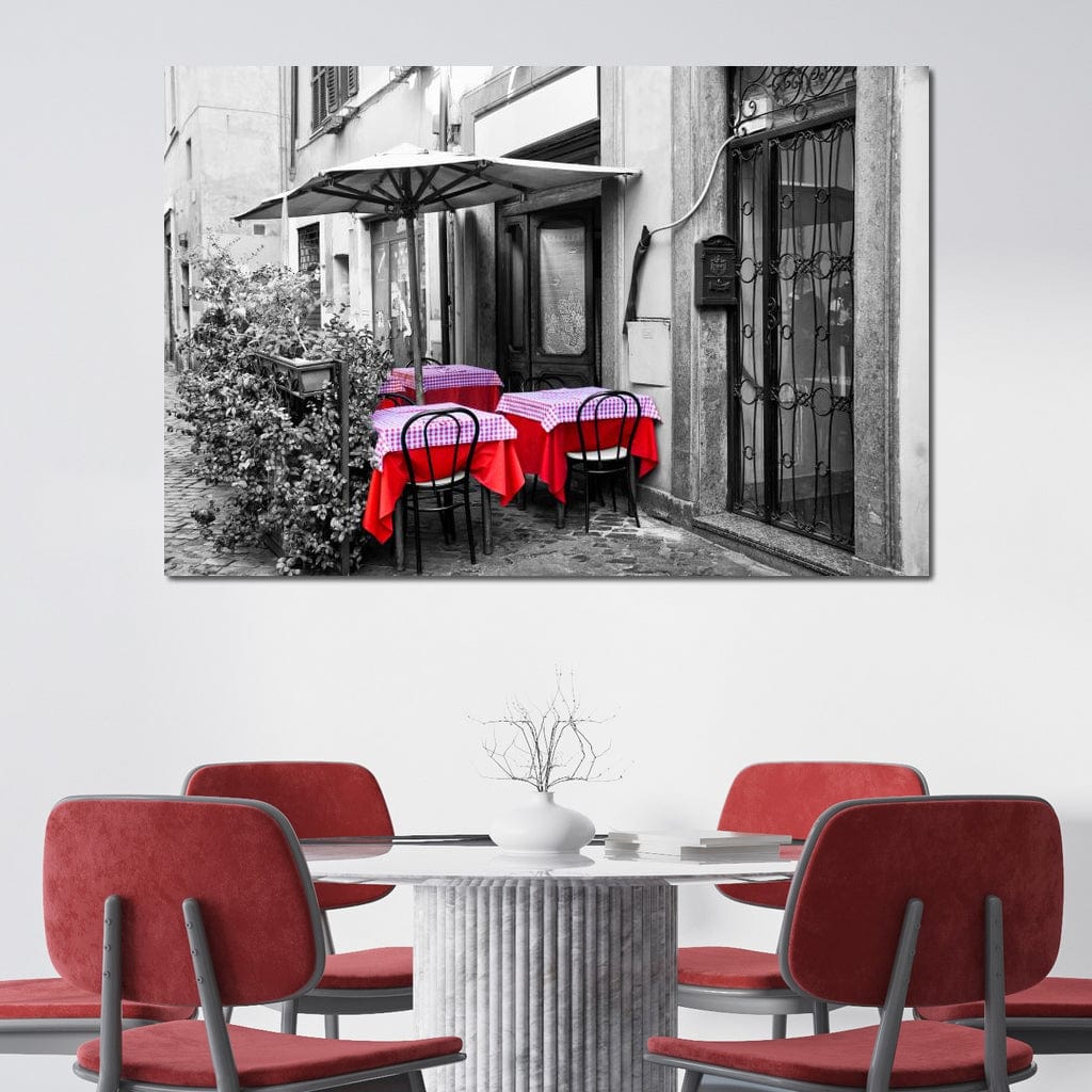 tablou canvas cu o cafenea pe o strada, redata in alb si negru, cu mese decorate cu rosu, intr-un peisaj vintage
