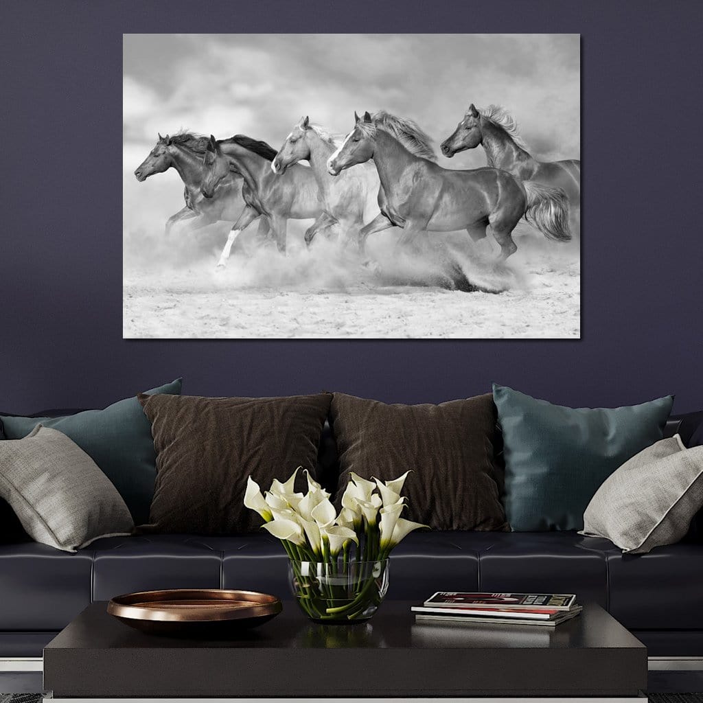 tablou canvas cu un grup de cai in galop prin nisip, redati in nuante de alb si negru, pe fundal cu nori