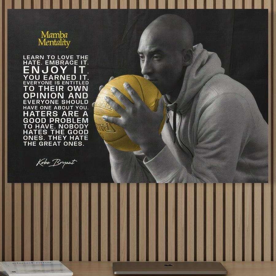 Un Tablou Canvas Premium LuxCanva® C1032 izbitor alb-negru cu Kobe "Mamba" Bryant într-un hanorac cu baschet și citat Mamba Mentality, așezat pe un perete din lemn - decor perfect pentru camera copilului, camera de jocuri sau bar. Brand: LuxCanva®.