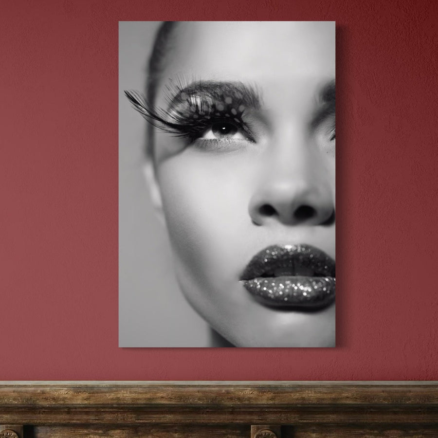 Tablou Canvas Premium LuxCanva® C1087 "Privire Strălucitoare" cu portret de femeie, tonuri alb-negru, gene dramatice și buze sclipitoare, expus ca artă pe perete roșu deasupra unei suprafețe din lemn.