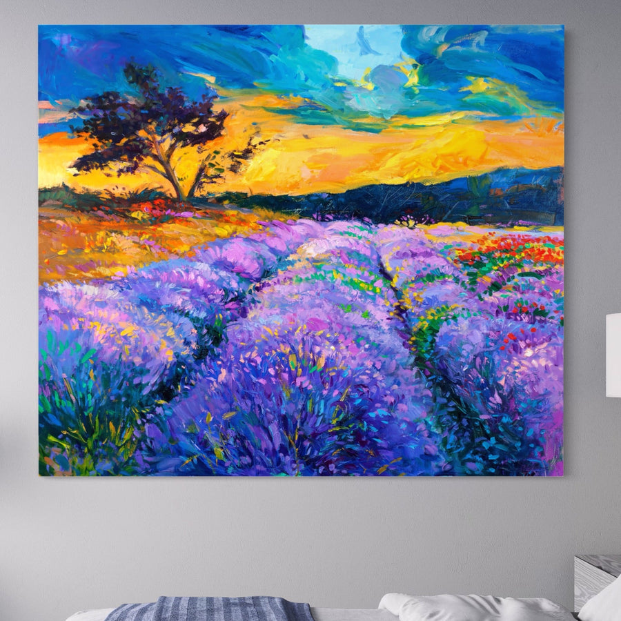 Tablou Canvas Premium LuxCanva® A1097, un peisaj vibrant cu lavandă și apus în nuanțe mov-lila, evidențiază flori mov și un copac sub un cer colorat, expus pe perete gri deschis deasupra patului. Brand: LuxCanva®.