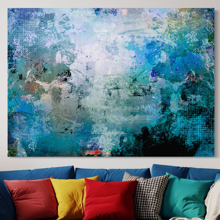 O pânză vibrantă LuxCanva® Tablou Canvas Premium A1087 în nuanțe abstracte de albastru colorat și multicolor atârnă deasupra unei canapele, cu nuanțele sale amestecate și aspectul texturat imprimate pe pânză de bumbac premium pentru un accent de decor elegant.