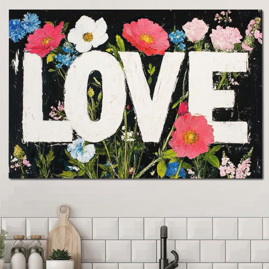 Tabloul LuxCanva® Tablou Canvas Premium LuxCanva® E1012, "Florile Iubirii", prezintă litere albe îndrăznețe "LOVE" încadrate de flori vibrante pe negru - perfect deasupra unui blat de bucătărie cu o placă de tăiat, un borcan și ustensile pe plăci albe.