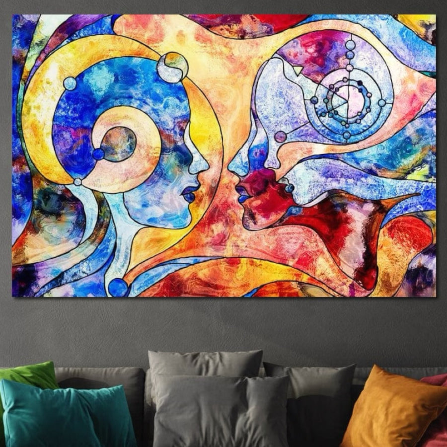 Deasupra canapelei, Tablou Canvas Premium "Dialogul Sufletelor" E1030 de la LuxCanva® prezintă două profiluri colorate, stilizate, cu forme vibrante în vârtej - o piesă spirituală atrăgătoare, care adaugă dualitate și mister decorului camerei de zi.