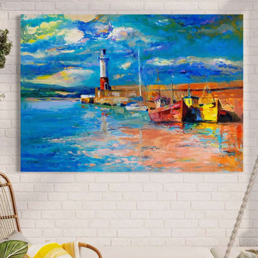 Pânza Tablou Premium LuxCanva® A1059, cu bărci vibrante într-un port, far, apus de soare și cer albastru, luminează un perete alb de cărămidă deasupra unei zone de relaxare confortabilă cu o pernă galbenă și albă.