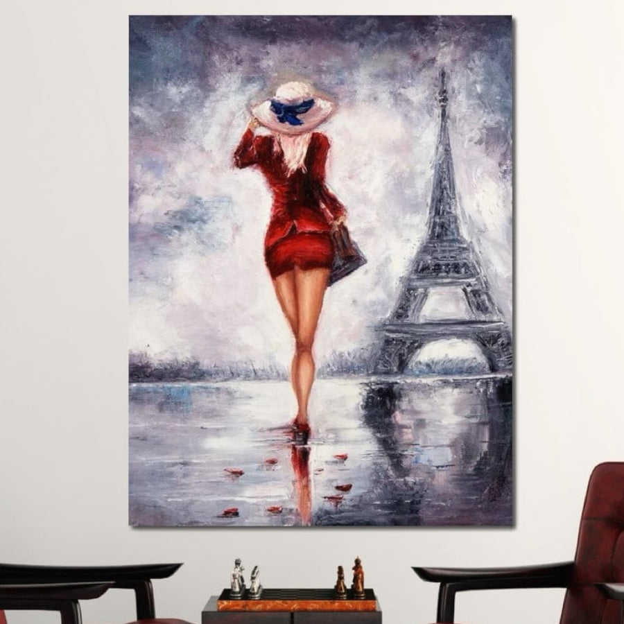Tablou Canvas Premium LuxCanva® E1047, Rendez-Vous la Turnul, prezintă o femeie pariziană într-o rochie roșie lângă Turnul Eiffel într-o zi ploioasă. Fabricată în România, această pânză vibrantă de la LuxCanva® adaugă un farmec elegant oricărei camere de zi.