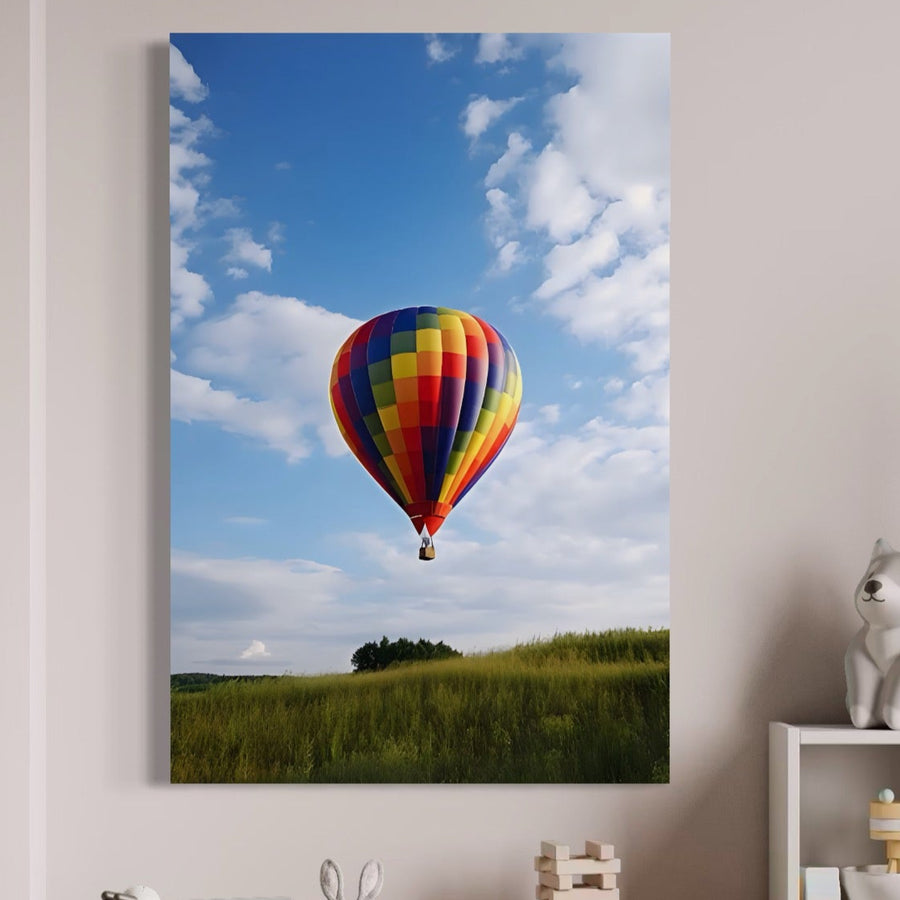 Tablou Canvas Premium LuxCanva® A1414, cu balon cu aer cald colorat deasupra unui câmp verde, aduce aventură și culori vibrante pe peretele tău. În cameră se observă și o figurină albă de pisică și obiecte mici.