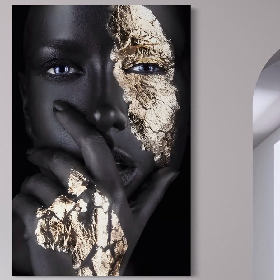 Tablou Canvas Premium LuxCanva® A1453 prezintă o femeie cu piele închisă, ochi albaștri, degete pe buze și accent aurie dramatic pe față și mână. Acest decor vibrant este perfect pentru living, oferind mister și frumusețe aparte.