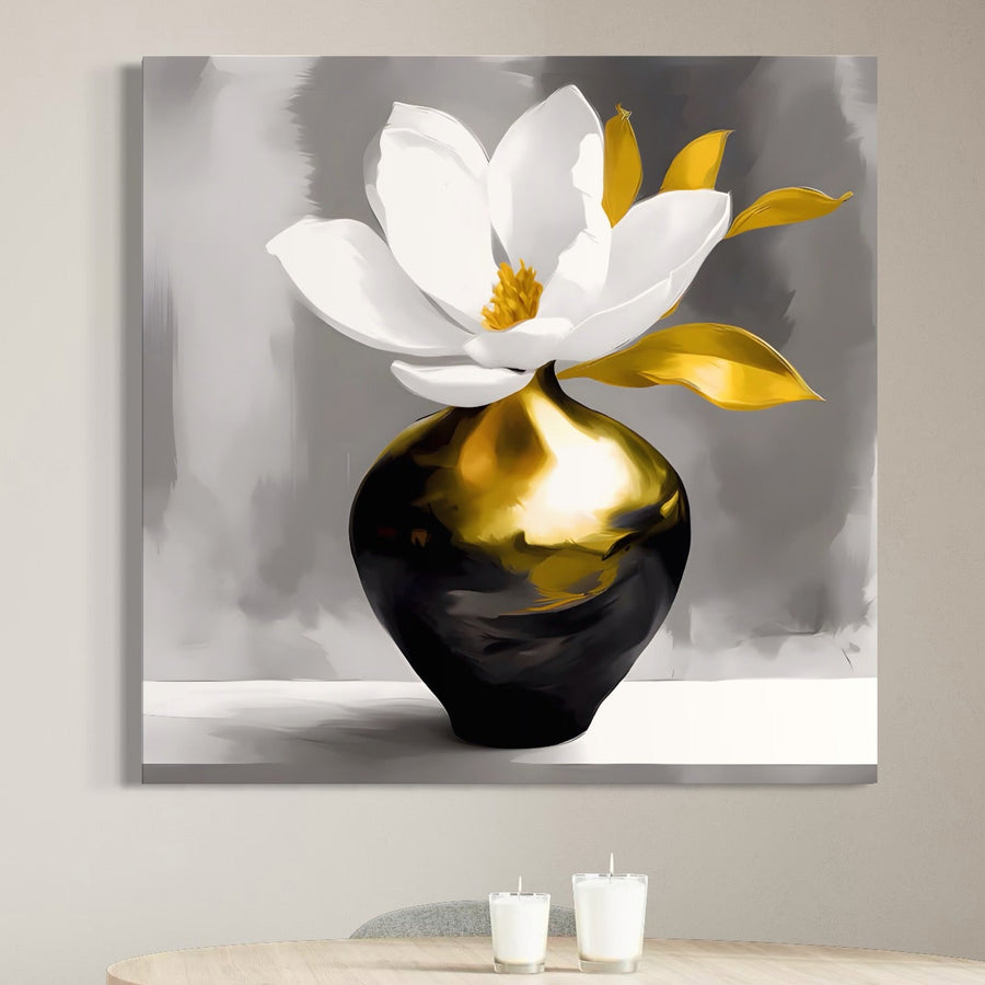 Tabloul LuxCanva® Tablou Canvas Premium A1576, "Armonie In Culori", prezintă o floare vibrantă albă și galbenă într-o vază lucioasă negru-aurie, expusă deasupra unei mese luminoase cu două lumânări albe pe un perete gri.