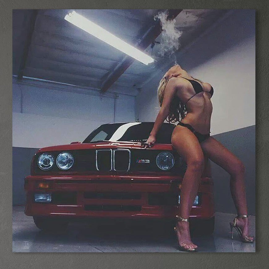 O femeie sexy în bikini negri și tocuri exhalează fum lângă un BMW M3 roșu într-un garaj - prezentat pe pânza LuxCanva® Premium, "Seductie pe Patru Roti" (P1062), perfectă pentru dormitoare sau sufragerii urbane.