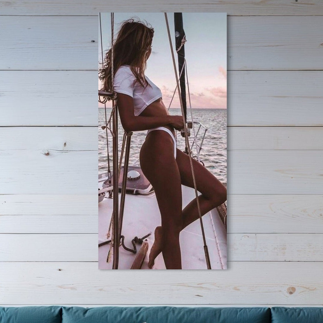 tablou canvas cu o femeie intr-un costum de baie alb, pe un iaht in mijlocul oceanului la apus de Soare