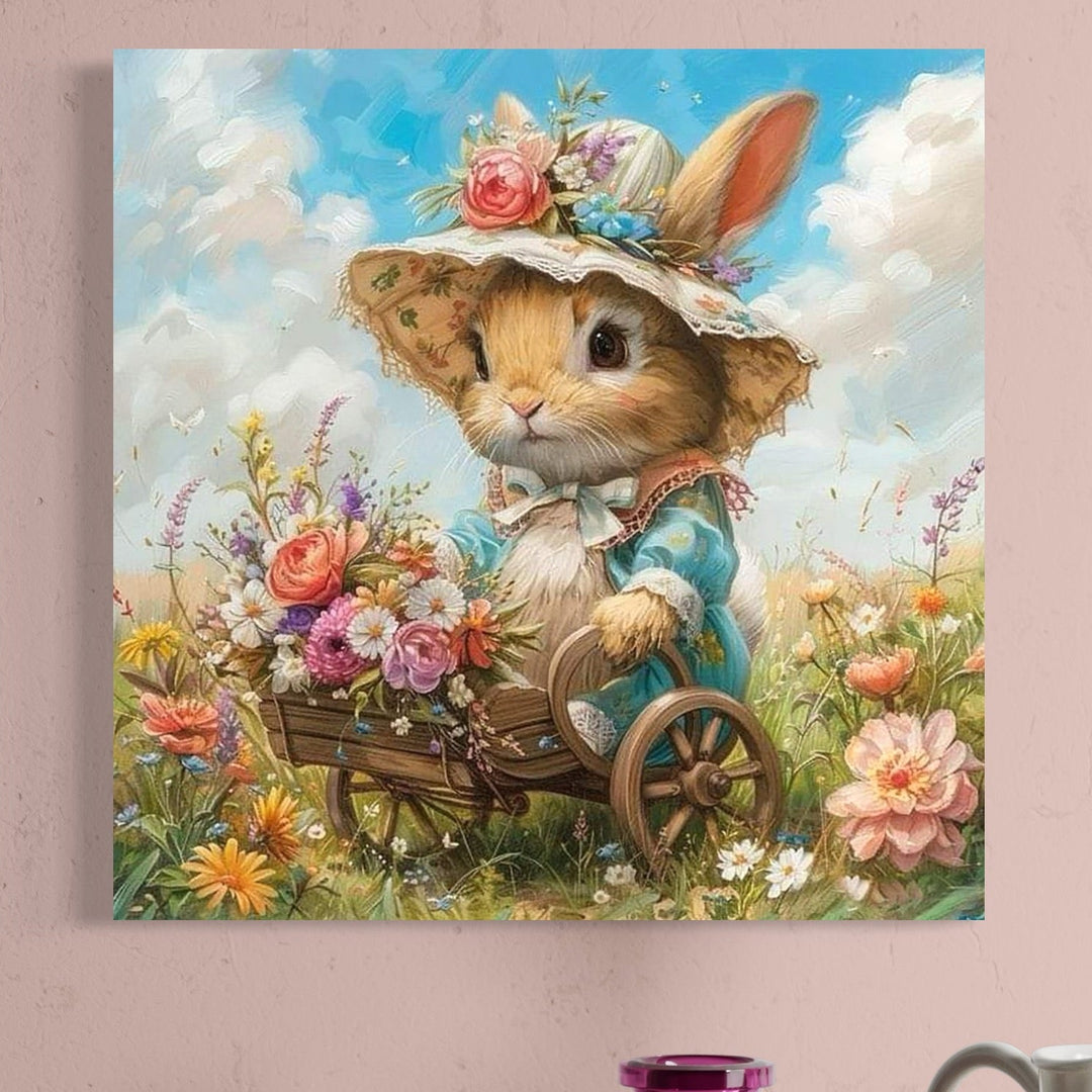 tablou canvas cu un iepuras cu rochita si palarie, plimband un carut de lemn, pe un camp cu flori