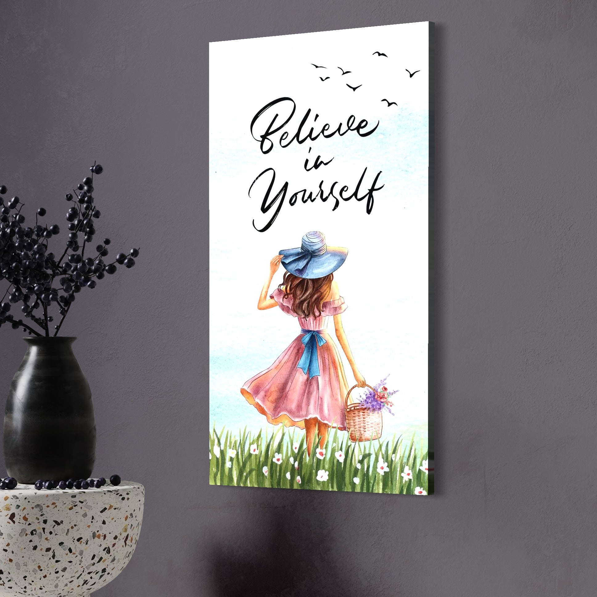 tablou canvas cu o fata cu rochie roz si palarie albastra, cu un cos cu flori colorate, pe fundal cu cer senin si un mesaj motivational