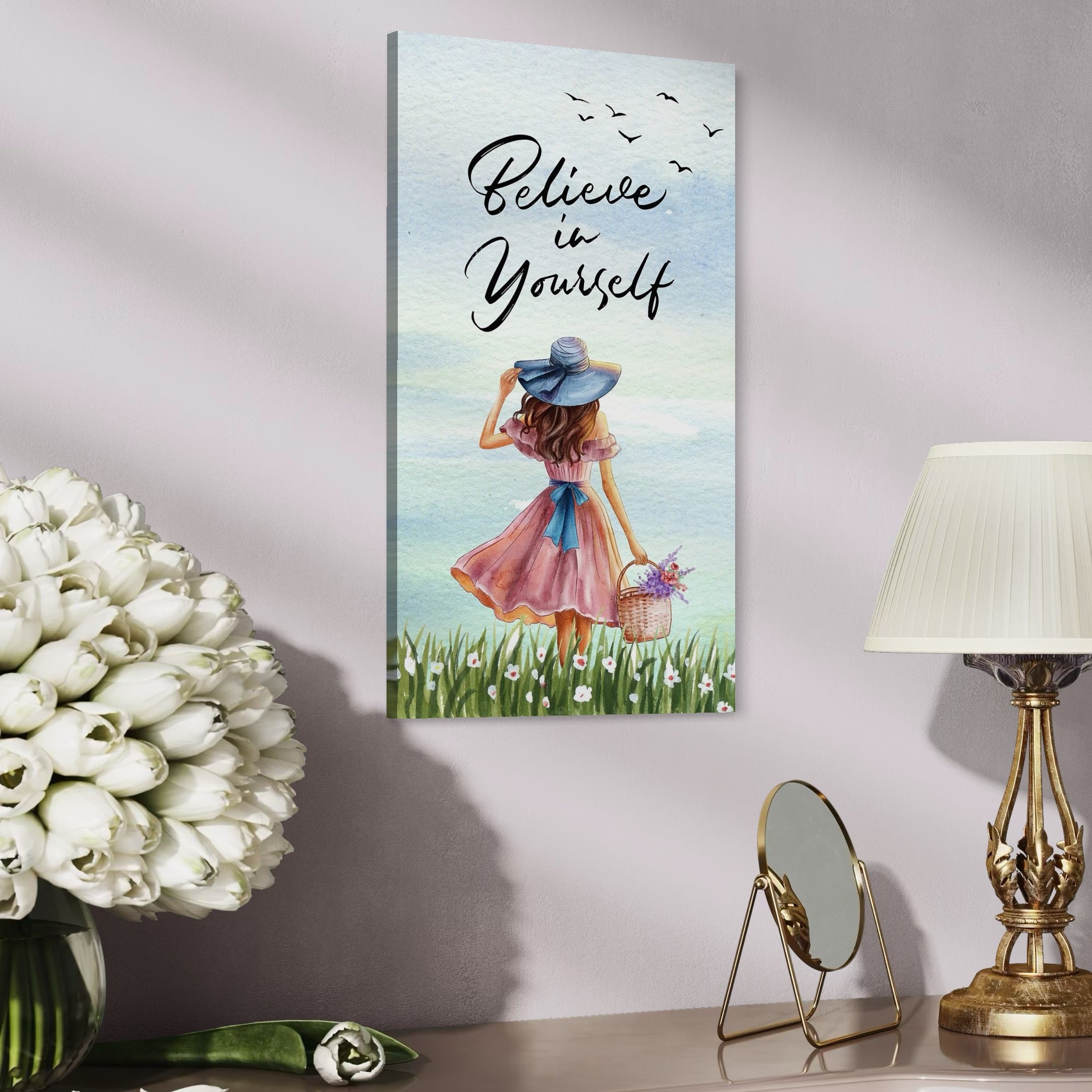 tablou canvas cu o fata cu rochie roz si palarie albastra, cu un cos cu flori colorate, pe fundal cu cer senin si un mesaj motivational