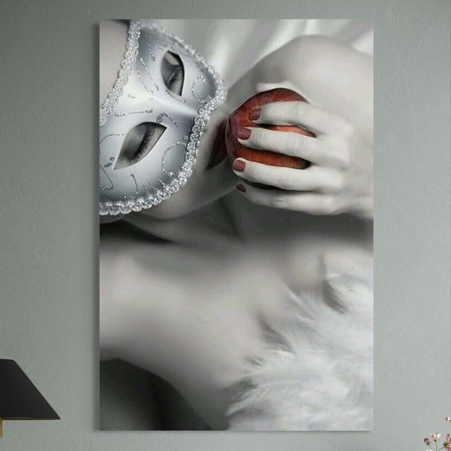 Descoperă "Tablou Canvas Premium LuxCanva® P1038 - Între Puritate și Păcat": o femeie cu masca decorativă argintie ține un măr roșu aprins la buze, imagine dramatică pe pânză bumbac, perfectă pentru living sau dormitor.