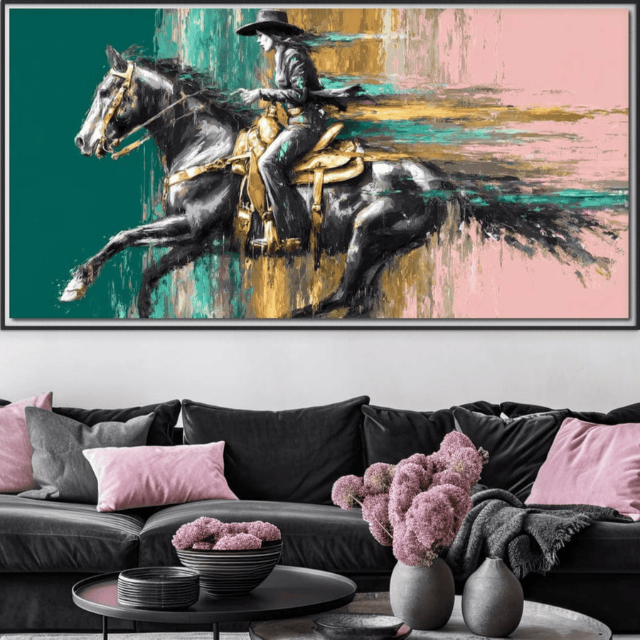 Tablou Canvas Premium LuxCanva® M1357 "Calaret Pierdut in Culoare", ce surprinde un cowboy și armasarul său în galop, cu tușe vibrante, este așezat deasupra unei canapele moderne cu perne roz-gri și o vază cu flori pe masă.