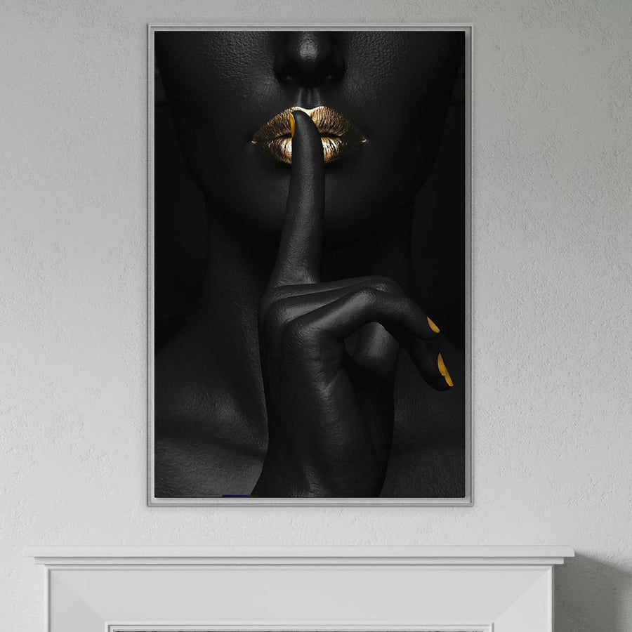 Tablou Canvas Premium LuxCanva® P1018 "Secretul Nostru", cu accente aurii și negre, prezintă buze senzuale într-un gest "shh", fiind perfect pentru dormitor sau living, montat pe un perete alb deasupra unei mantale albe.