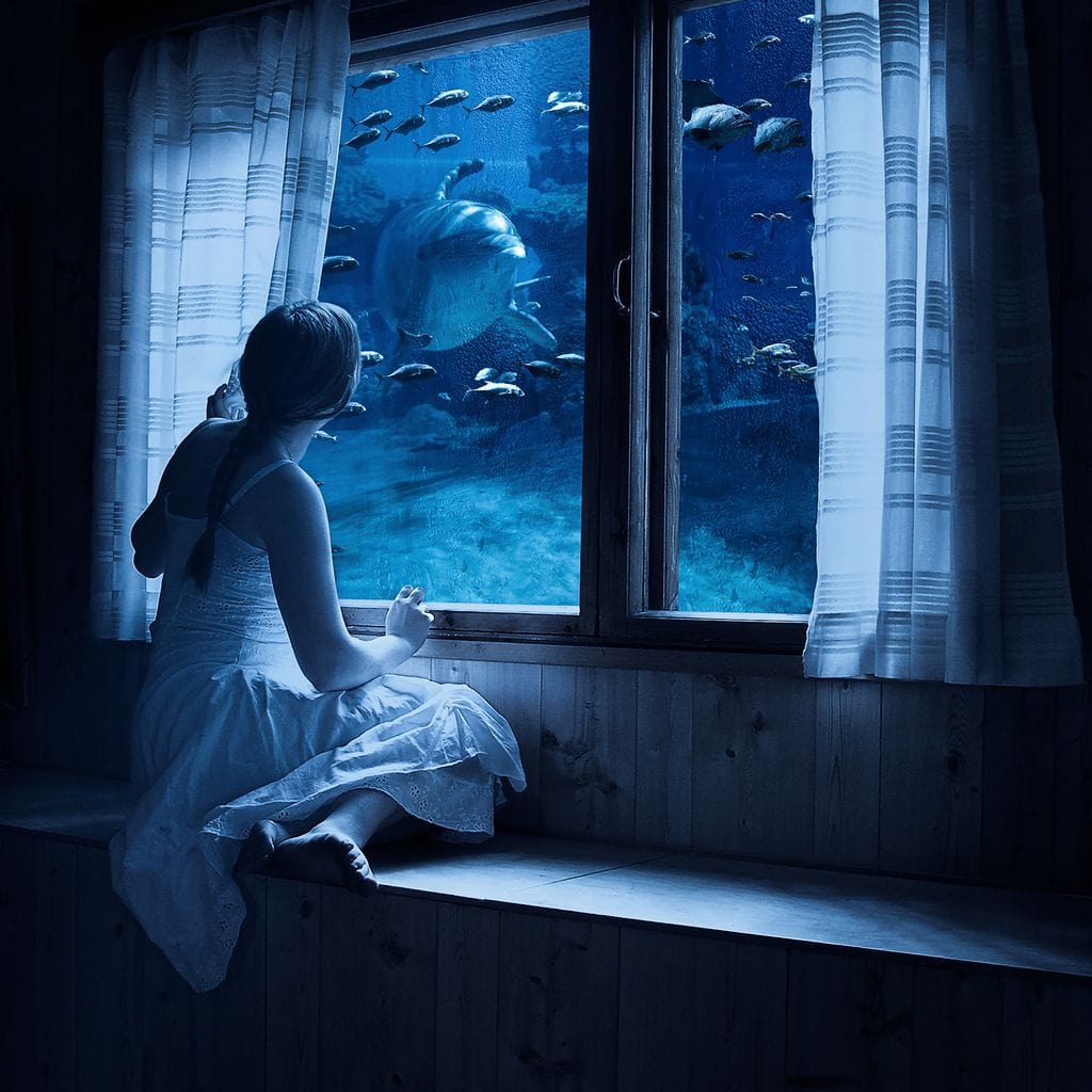 tablou canvas cu un copil privind adancurile oceanului cu pesti si rechini printr-o fereastra