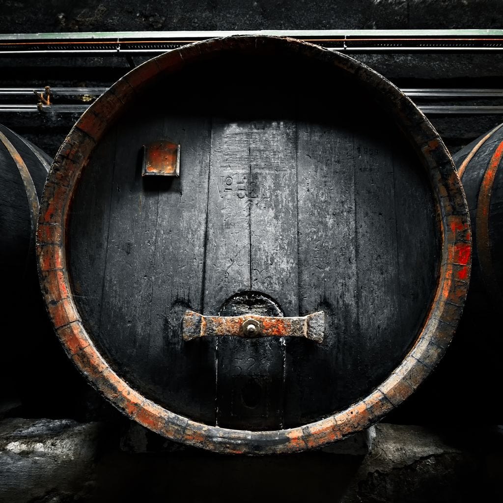 tablou canvas cu butoaie din lemn negre, pline cu vin, marcate in dungi rosii intr-un cadru traditional