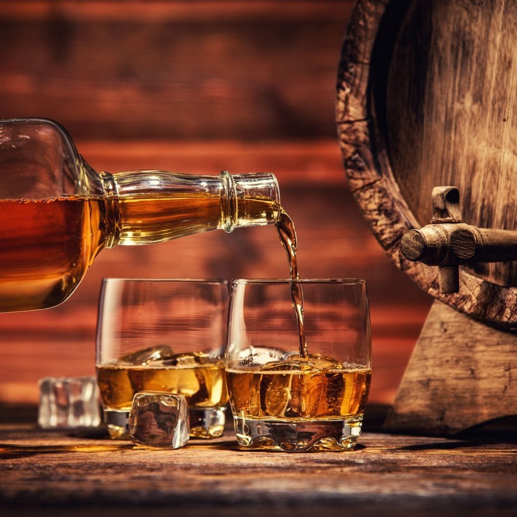 tablou canvas cu un butoi de lemn, o sticla de whisky turnand in doua pahare cu gheata, pe fundal rustic in nuante calde 