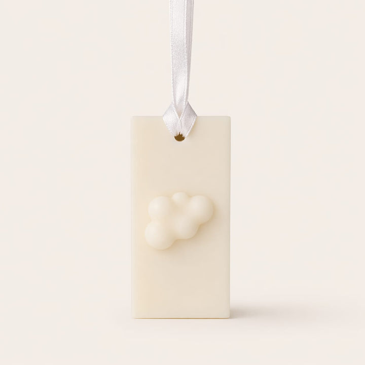 Odorizantul LuxCanva® Dulap/Sertar/Pantofar GeRa Essence, realizat manual din ceară naturală (30g), prezintă un model de nori și este agățat de o panglică albă din satin. Parfum: bumbac, flori de cires, bujori, parfum curat.